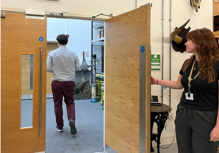 A tour guide holding the door open to exit the Leeds Discovery  Centre store room