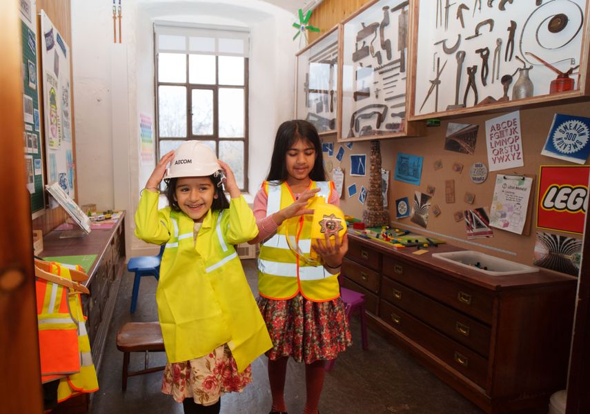 Two children in high-vis fancy dress and hard hats playing in Leeds Industrial Museum