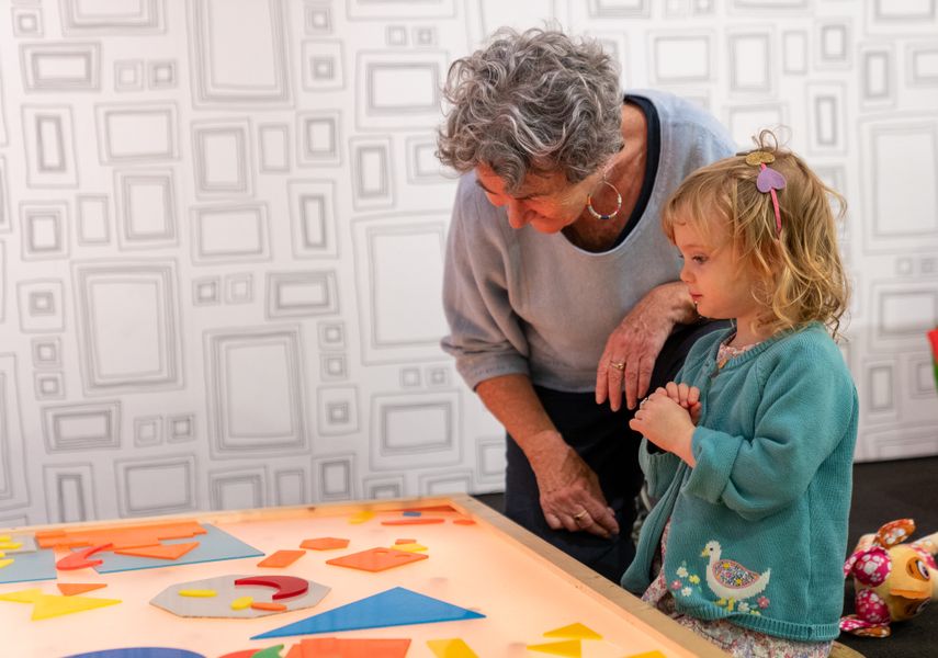 Adult and child looking at colourful shapes on a table