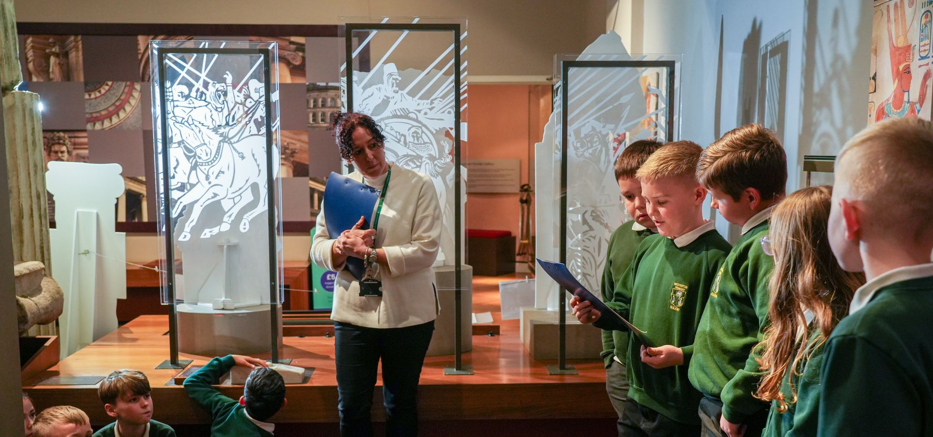 A teacher and students doing a workshop activity in the Ancient Worlds gallery at Leeds City Museum