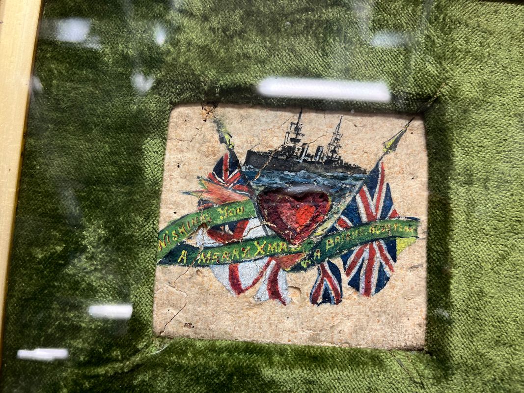 The decorated biscuit from 1914, beautifully painted with an image of a battleship and carrying an inscription that reads ‘Wishing you a Merry Christmas and a bright new year’.