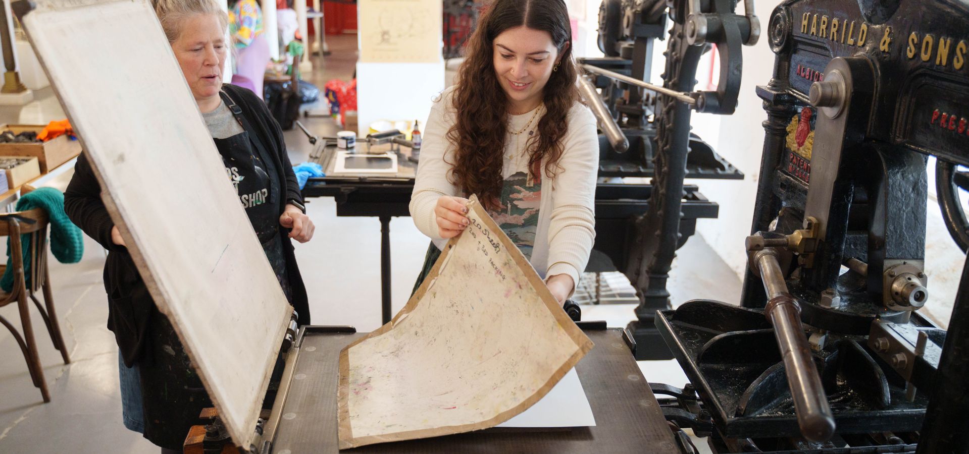 A woman lifting a piece of paper off the Albion printing press