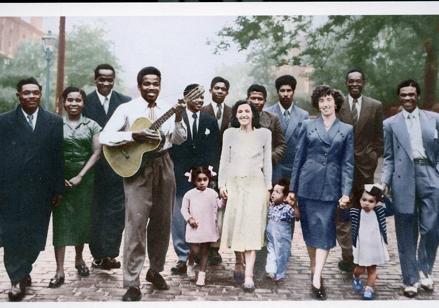Group of men, women and children in Leeds, one man is holding a guitar