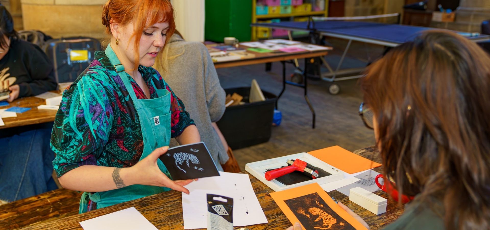 Two people sat at a table making zines