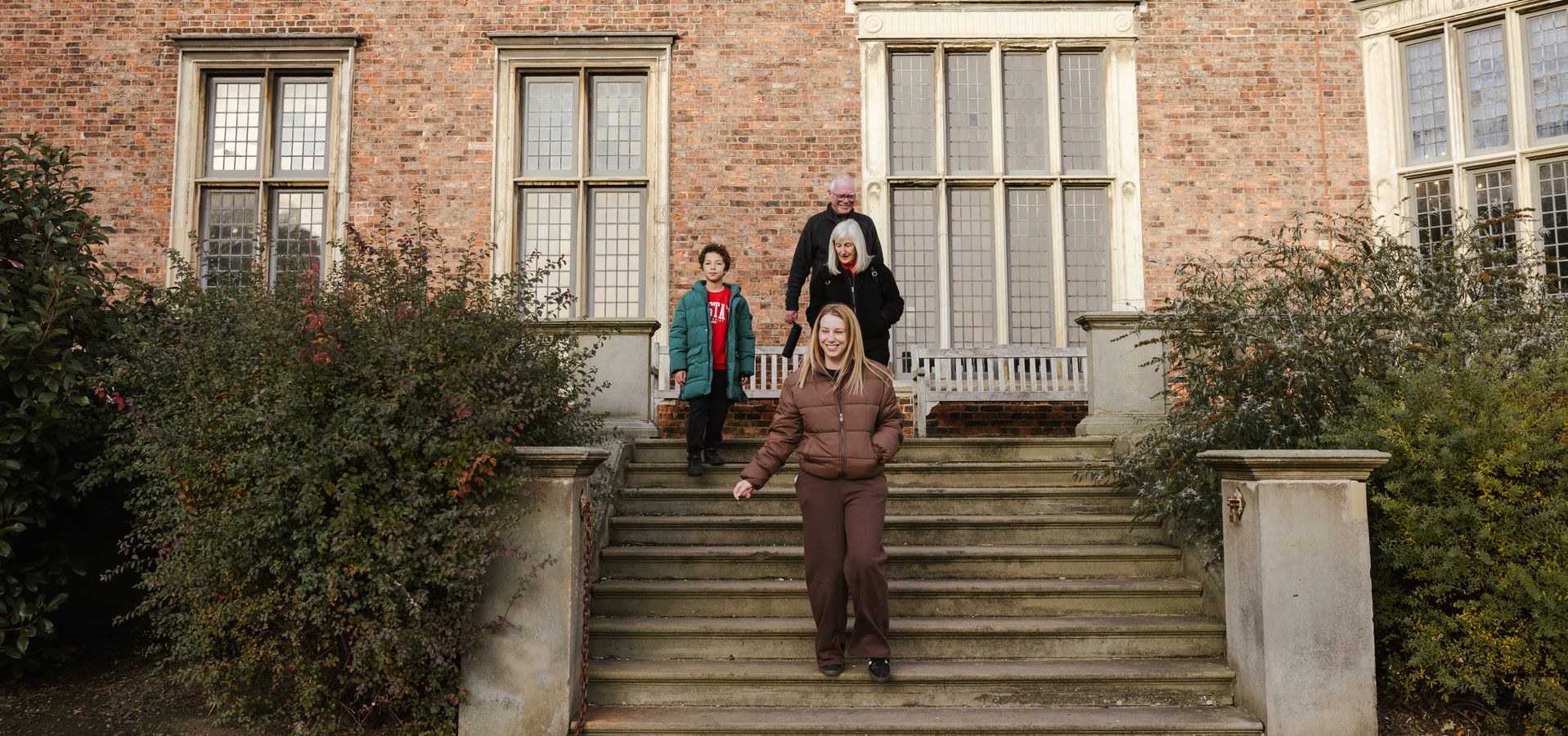 3 adults and a child walking down Temple Newsam house terrace steps