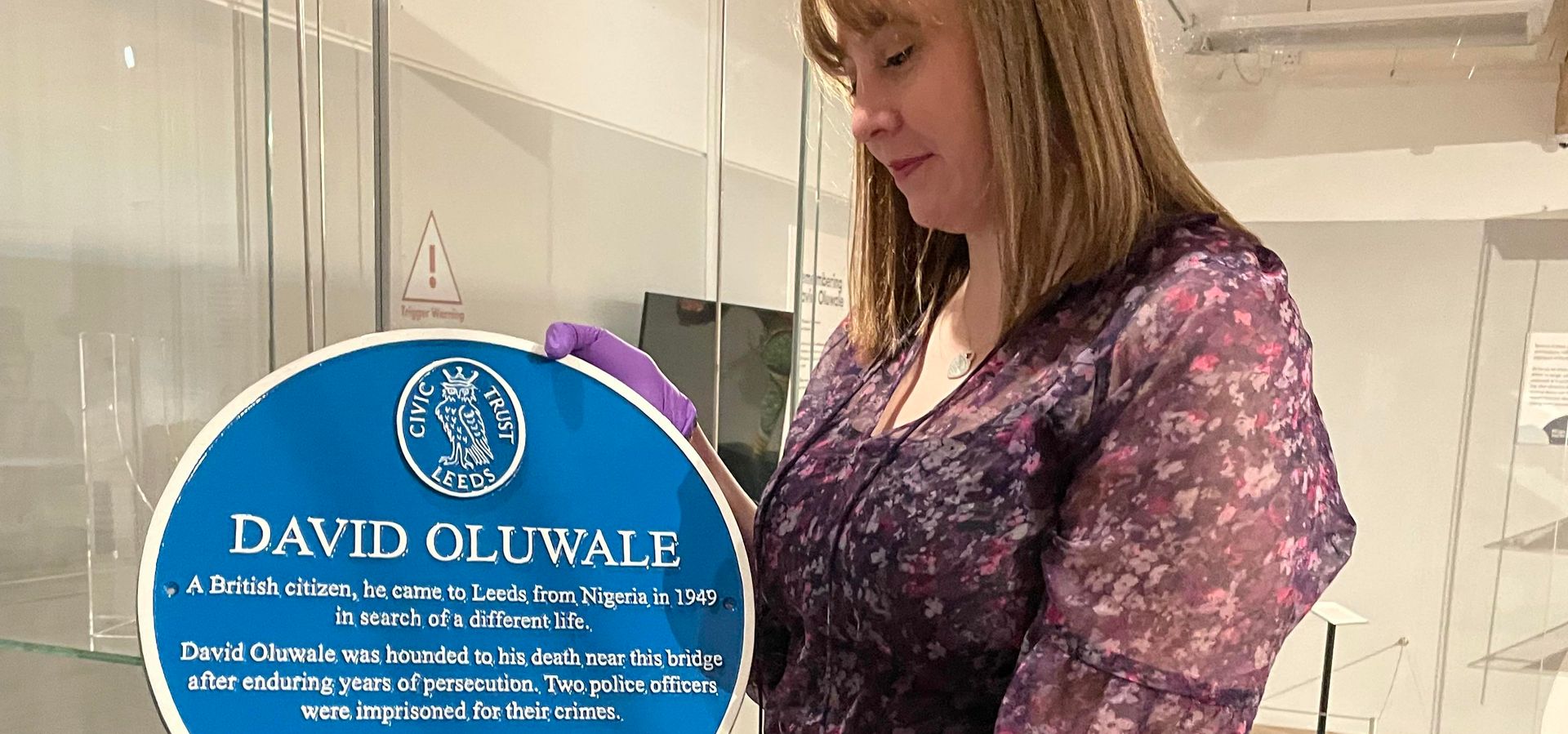 Preservative Party member Lauren Theweneti with the replica of David Oluwale's blue plaque, on display in Overlooked at Leeds City Museum.