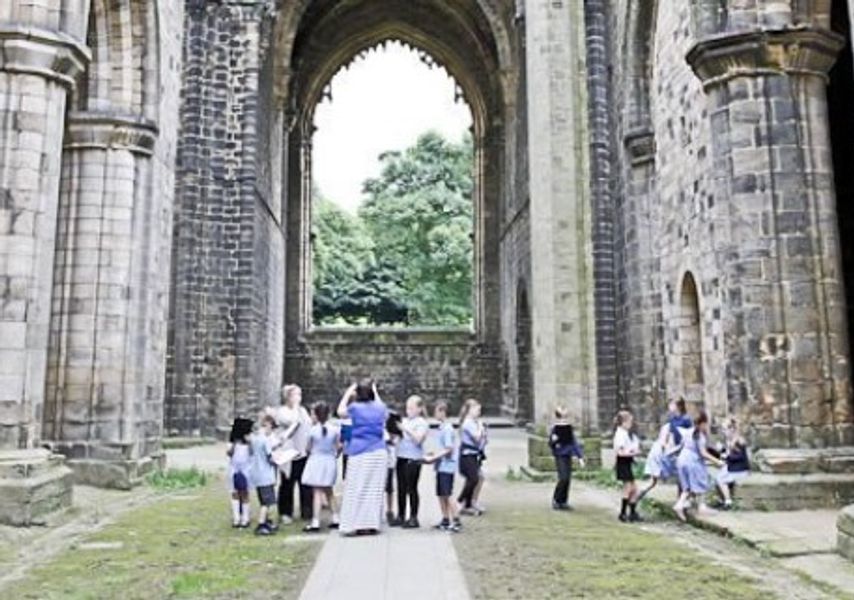 A class of children in a ruined Abbey