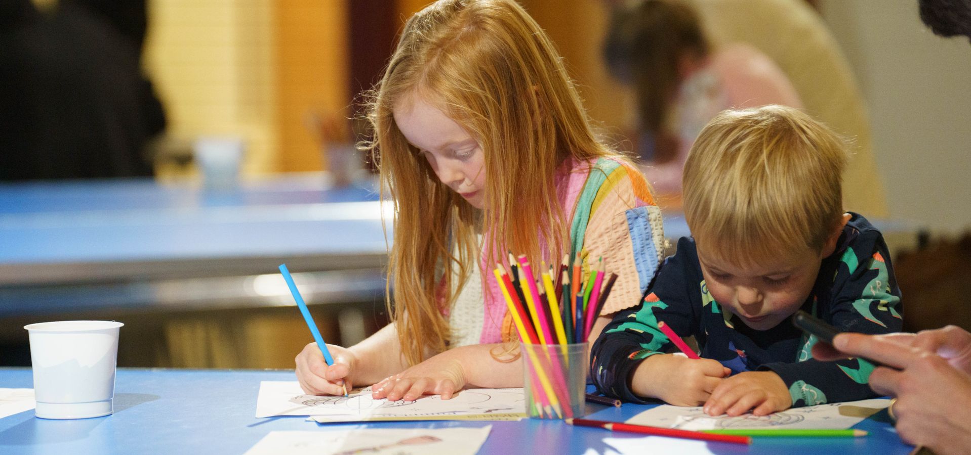 Two children colouring on a blue table
