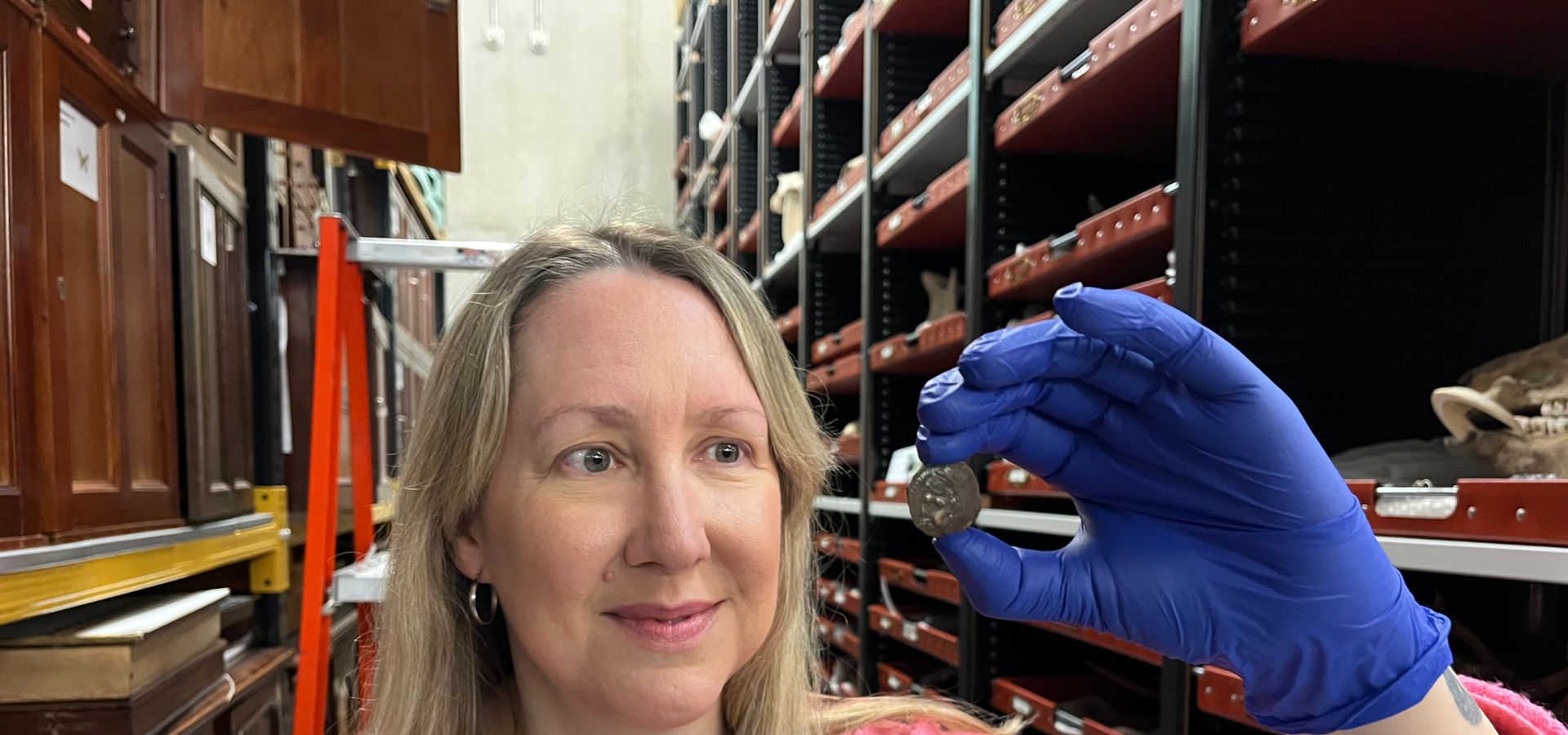 Curator of Archaeology and Numismatics in the collection store holding a small coin
