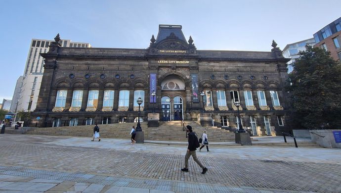 The front façade of Leeds City Museum with the sun rising behind