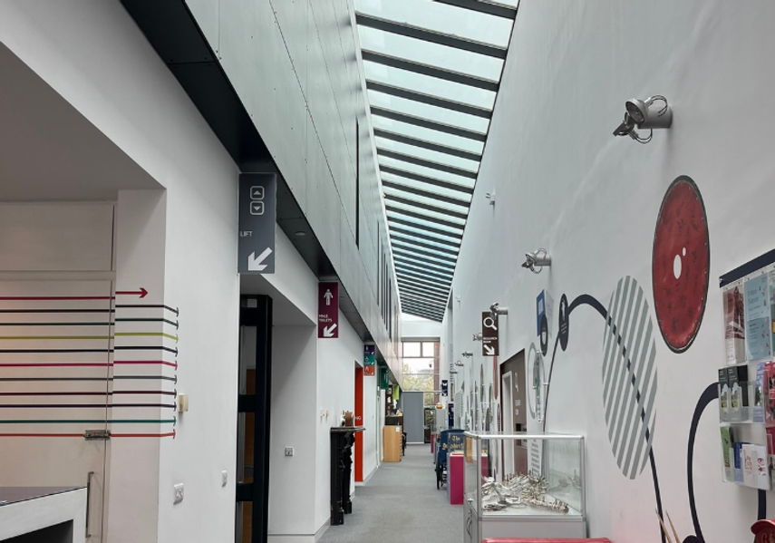 The main corridor in Leeds Discovery Centre with a red sofa on the right and toilets signs on the left