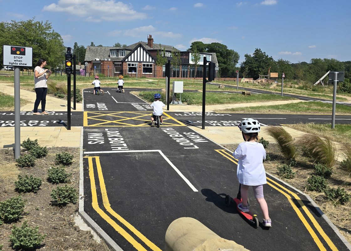Children scootering and biking on the learn to ride area