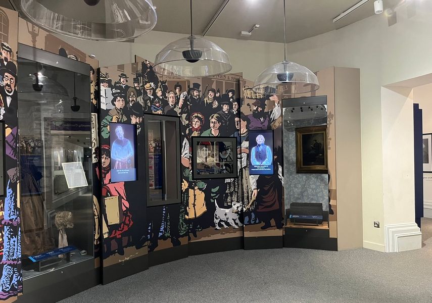 Displays from The Leeds Story Gallery that feature artefacts from the Victorian period as well as video of reenactors on screens.