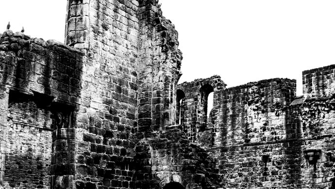 A black and white image of ruins with line markings on the grass in front
