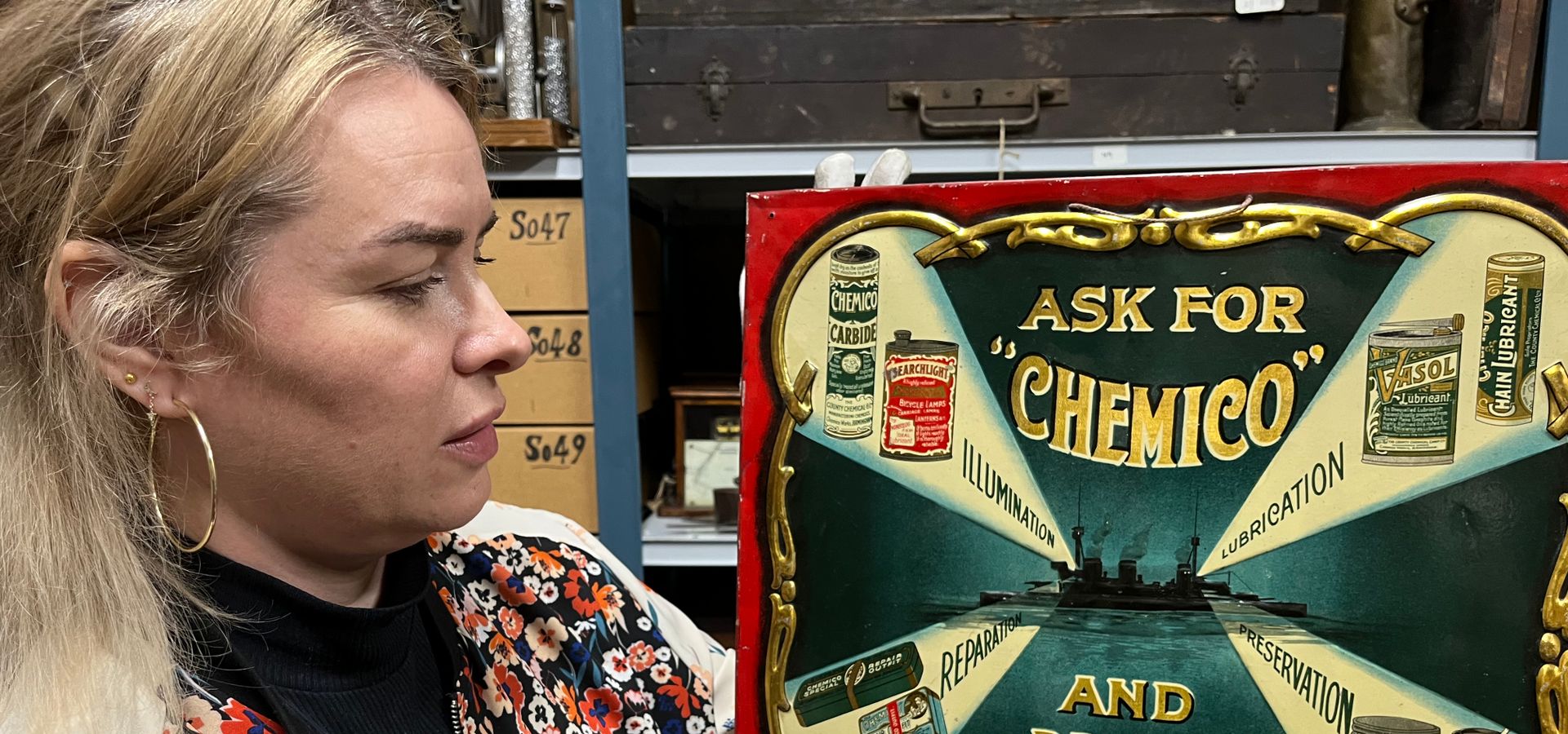 A curator holding a 'ask for "chemico"' advertisement sign