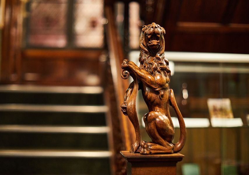 A wooden carved lion on a stairway hand rail