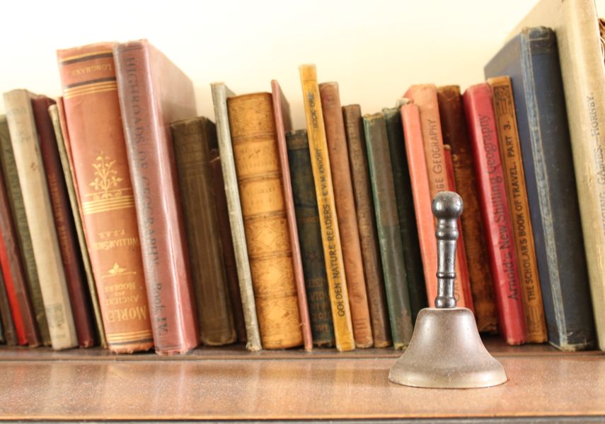 A row of books with a hand bell in front of it