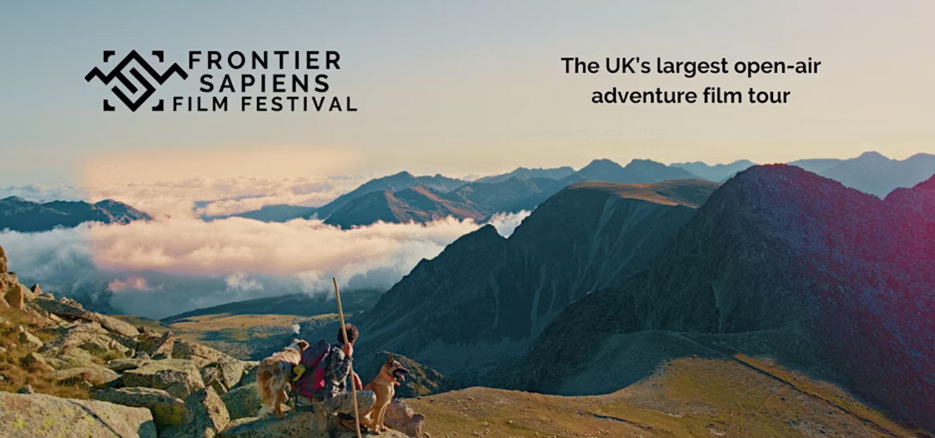 Beautiful mountain landscape with man and two dogs. Text reads "The UK's largest open-air adventure film tour"