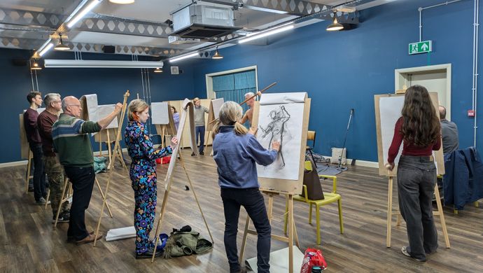 A group of people stood at easels doing life drawing