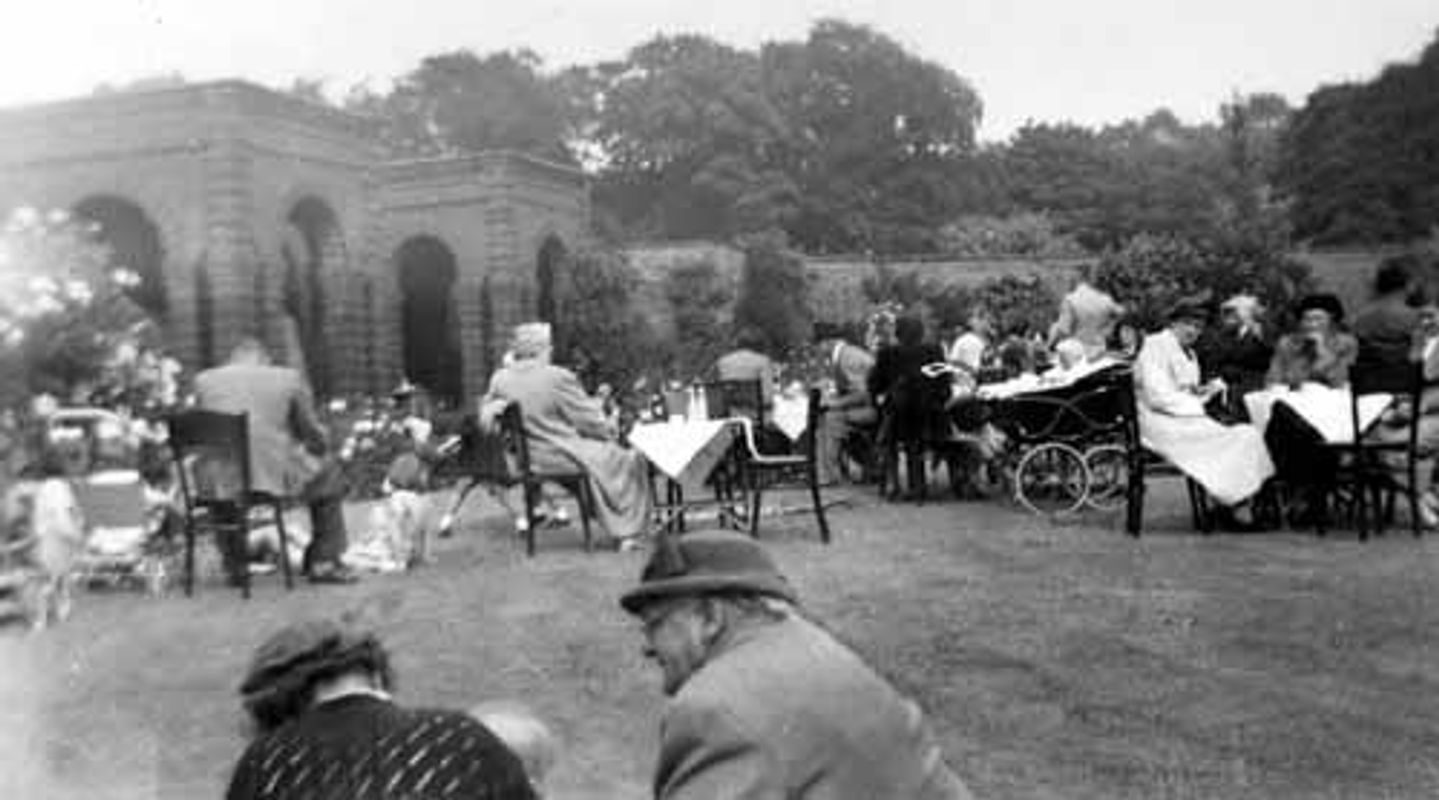 Image from late 1940s/early 1950s, showing people seated at tables enjoying a summer garden party in the walled garden of Lotherton Hall. Credit: Leodis.net