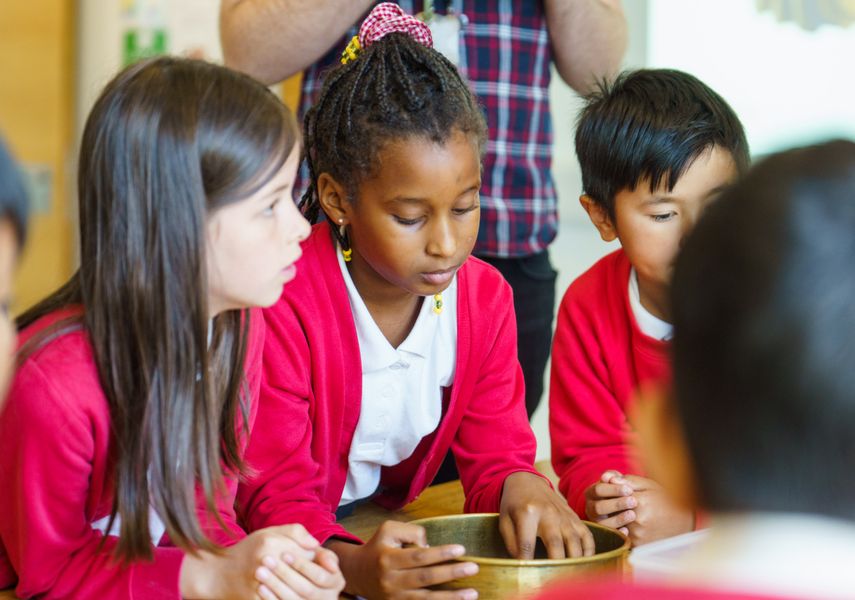 Three schoolchildren looking at objects