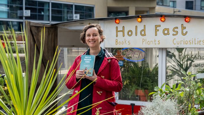 SJ Bradley holding her book on the HoldFast bookshop boat in Leeds