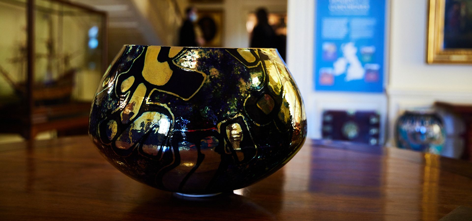 A black and gold studio pottery piece on a wooden table in Lotherton Hall