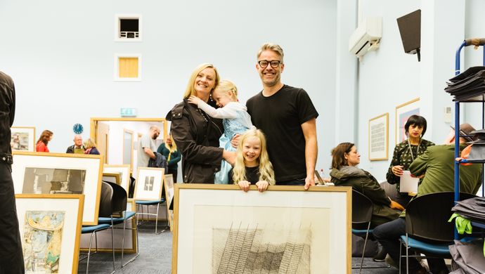 A couple and a child stood with their picture library print in Leeds Art Gallery