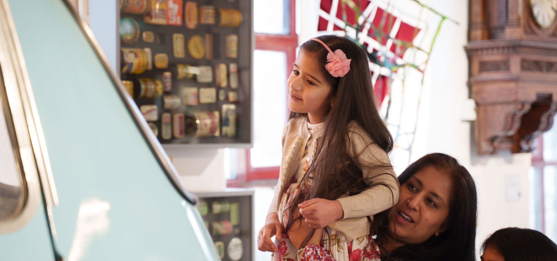 An adult lifting up a child to look at a car in the museum
