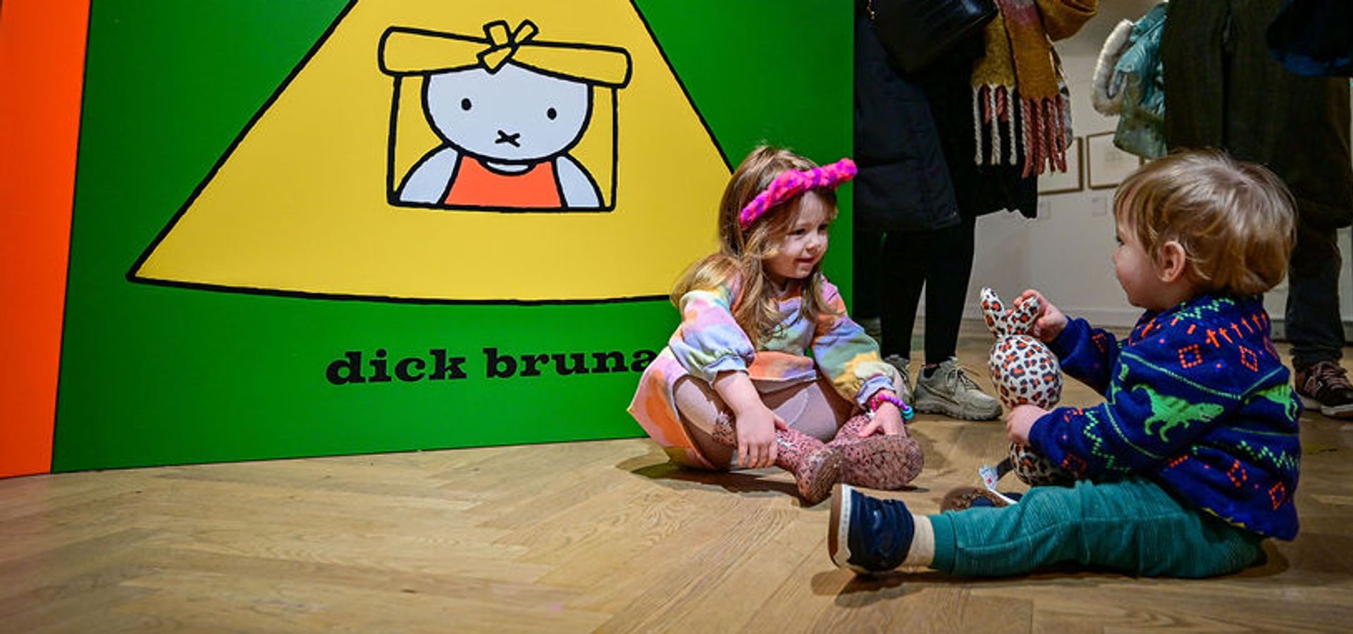Two toddlers sat on the floor infront of an extra large miffy book