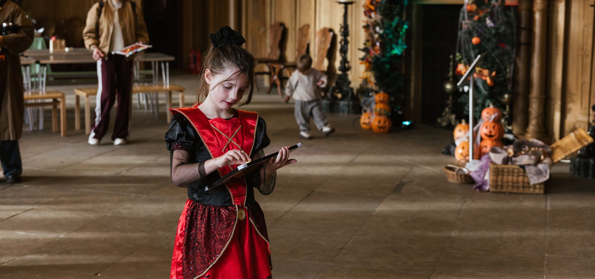 A child in fancy dress doing an activity on a clipboard in Temple Newsam