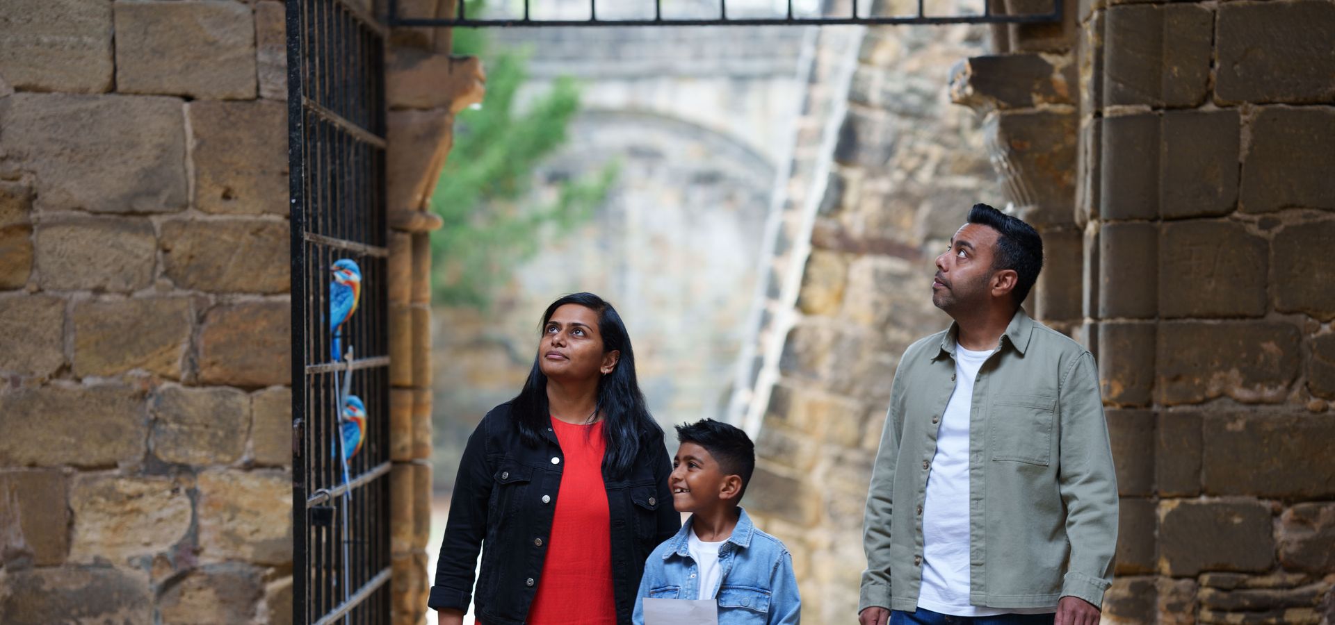 2 adults and a child look around in Kirsktall Abbey