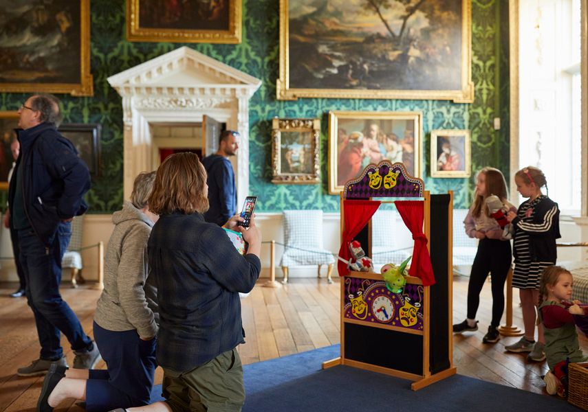 A family play with a toy puppet show theatre inside Temple Newsam.