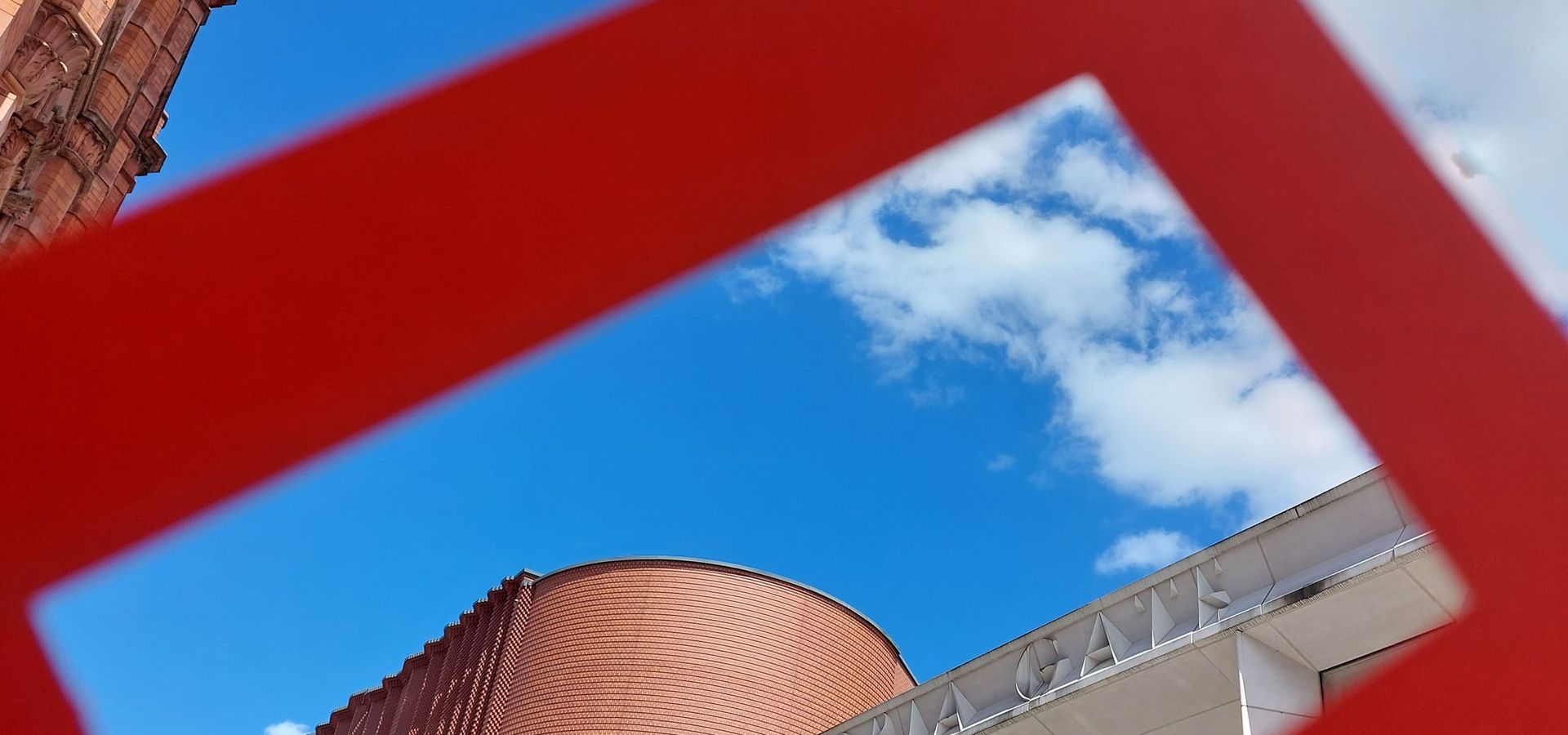 A red frame held up against the sky and the Victoria Gate sign in Leeds