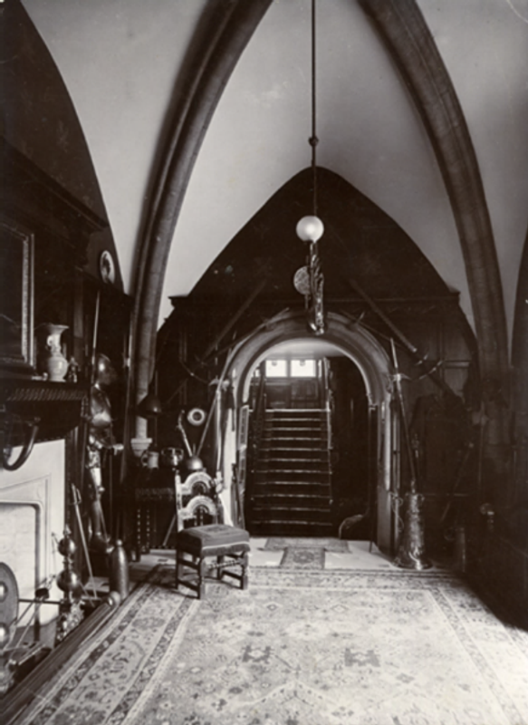 A view of the staircase from the Norman Hall, circa 1890s. The lower portion of the stained-glass windows depicting Saladin and Henry II can be seen through the arch. 