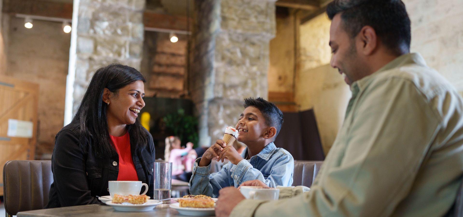 Two adults and a child sat at a cafe table eating
