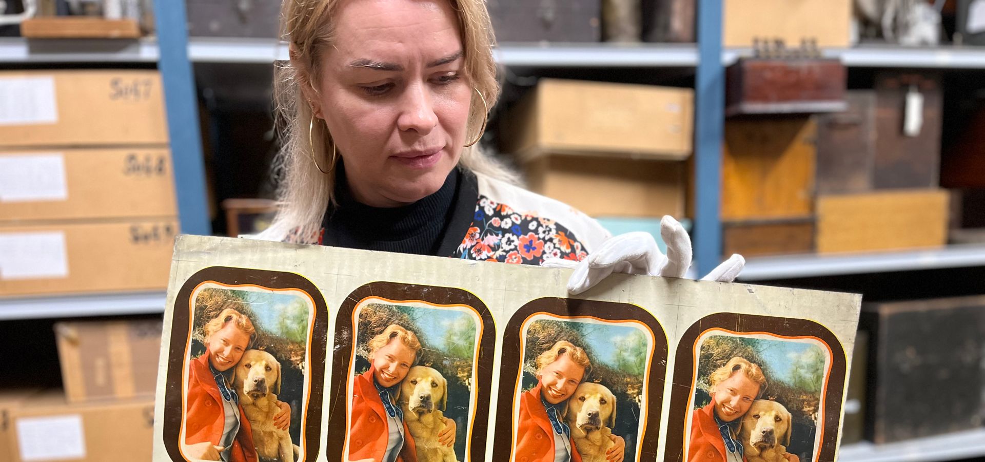 A curator holding portraits of a woman and a dog