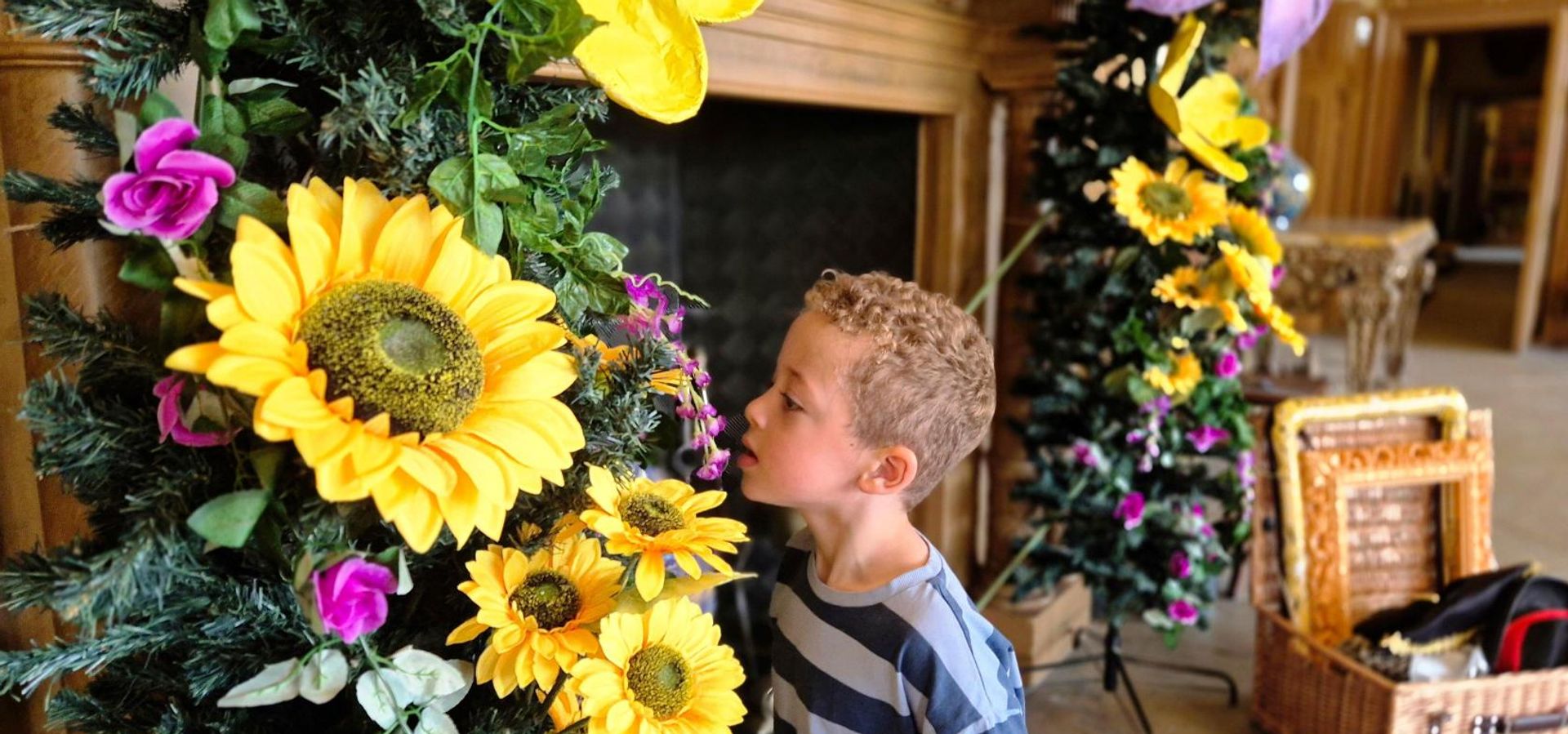Child looking closely at flower garland around a fireplace