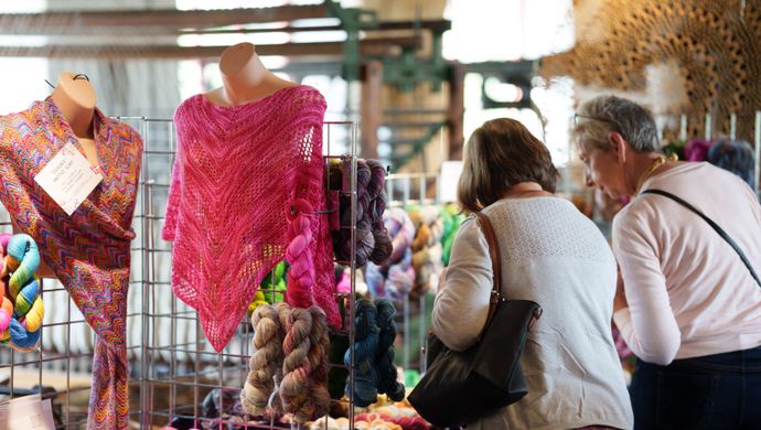 Two people browsing wool clothing stalls