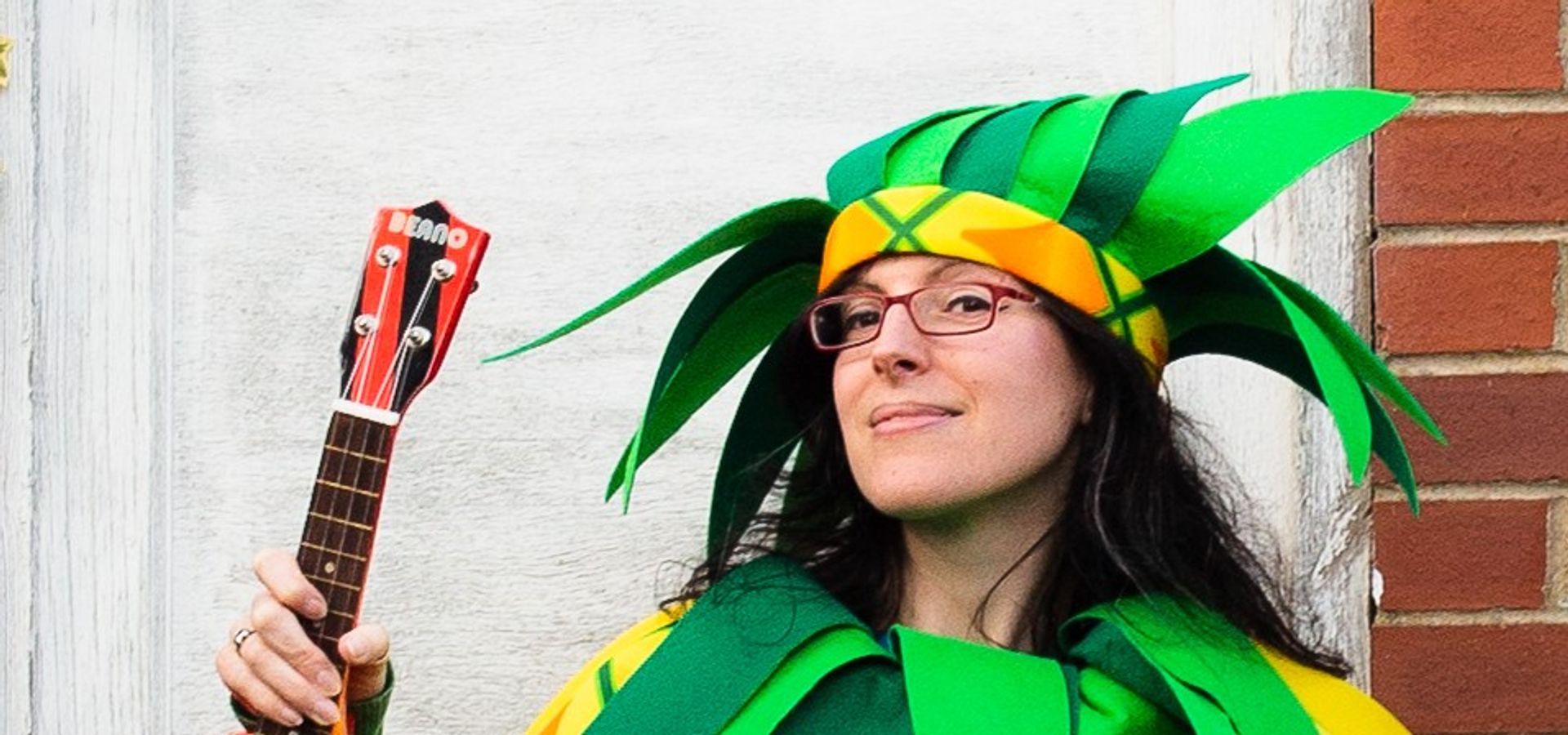 Nicky Bray in a pineapple costume holding a miniature guitar