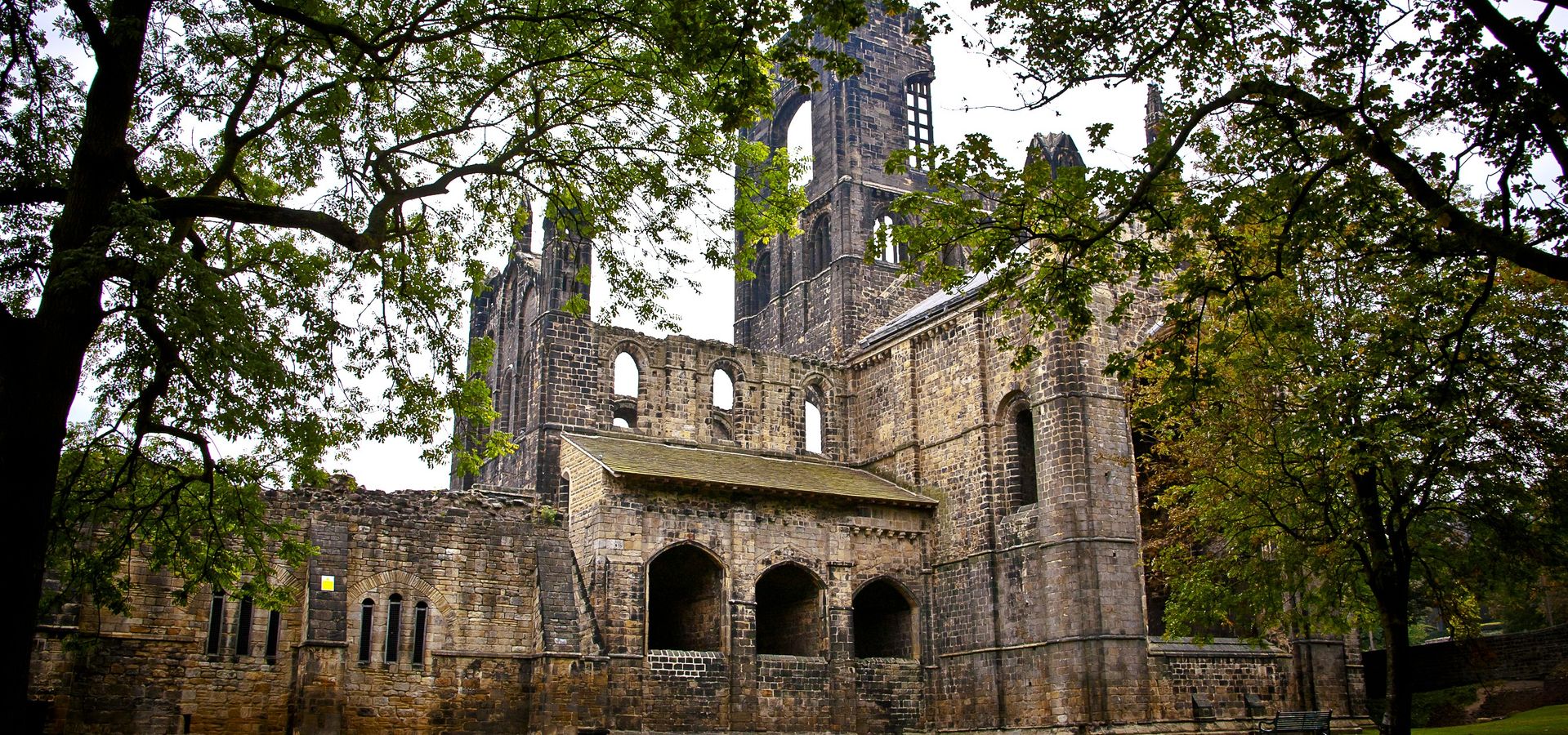 The view of Kirkstall Abbey ruins peaking through tree branches