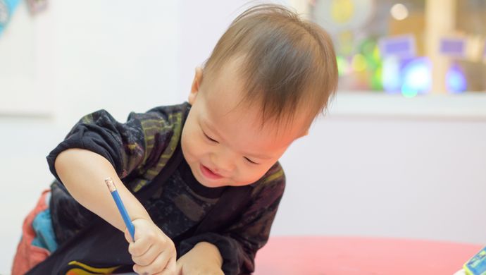 a toddler drawing on a piece of paper