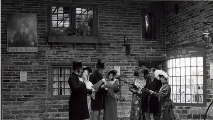 A group of people stood in Abbey House Museum streets reading