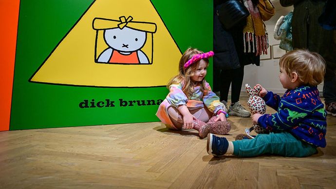 Two toddlers sat on the floor infront of an extra large miffy book