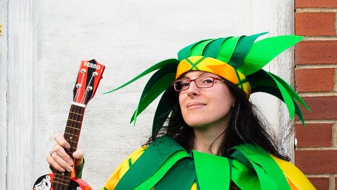 Nicky Bray in a pineapple costume holding a miniature guitar