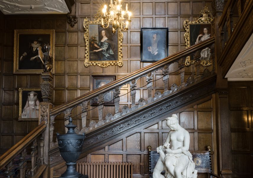 A wooden tudor stairway with paintings and sculptures in