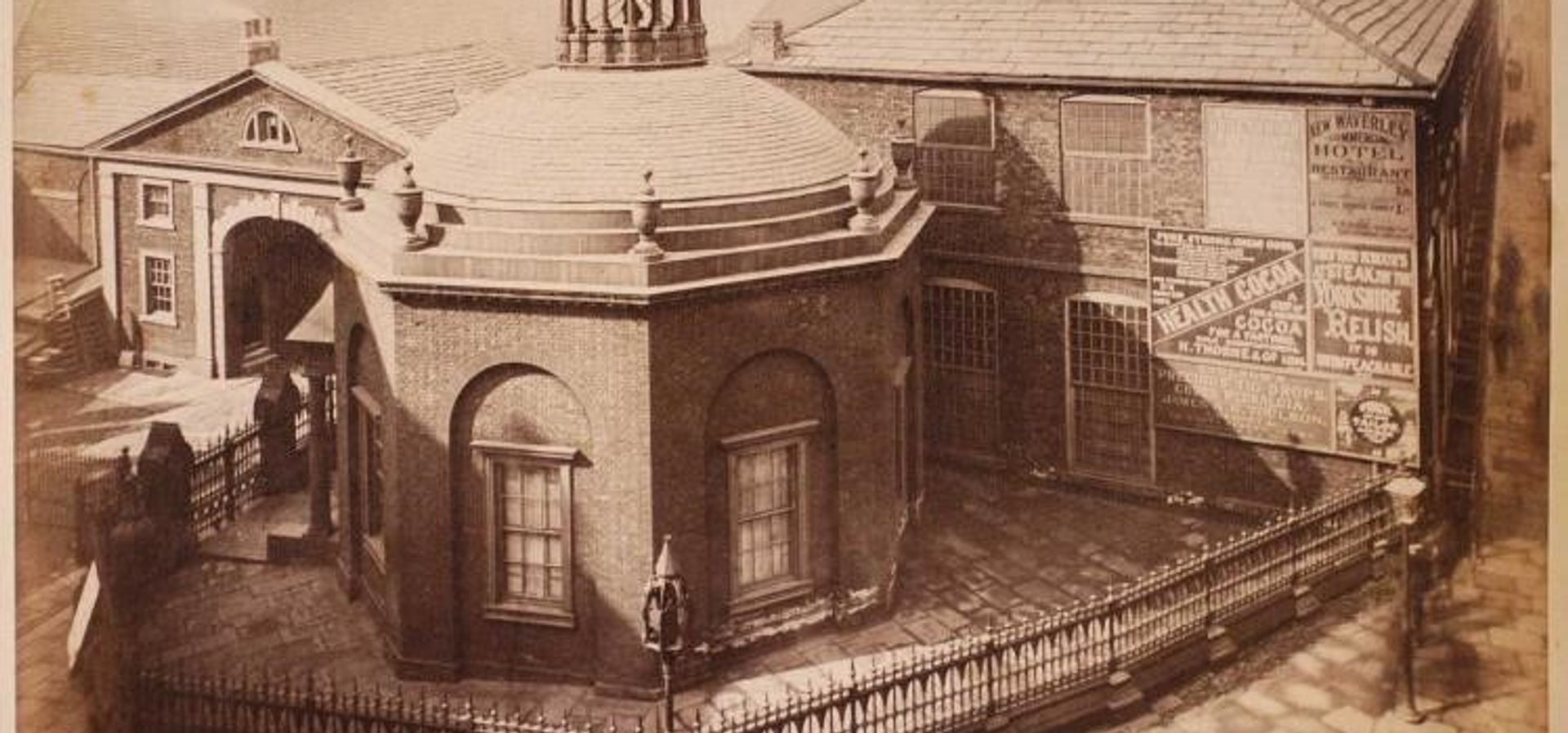 A round shaped building with 2 buildings in the background