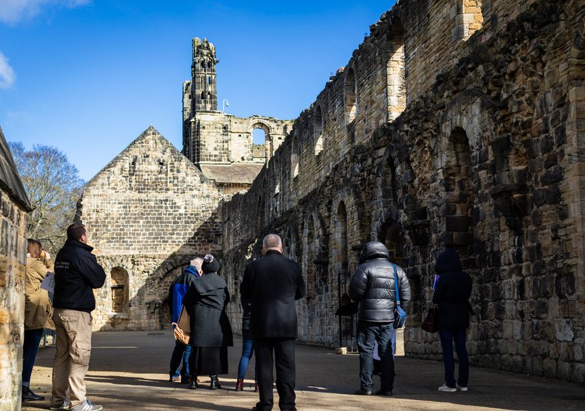 A group of people wandering around ruins in Kirkstall Abbey