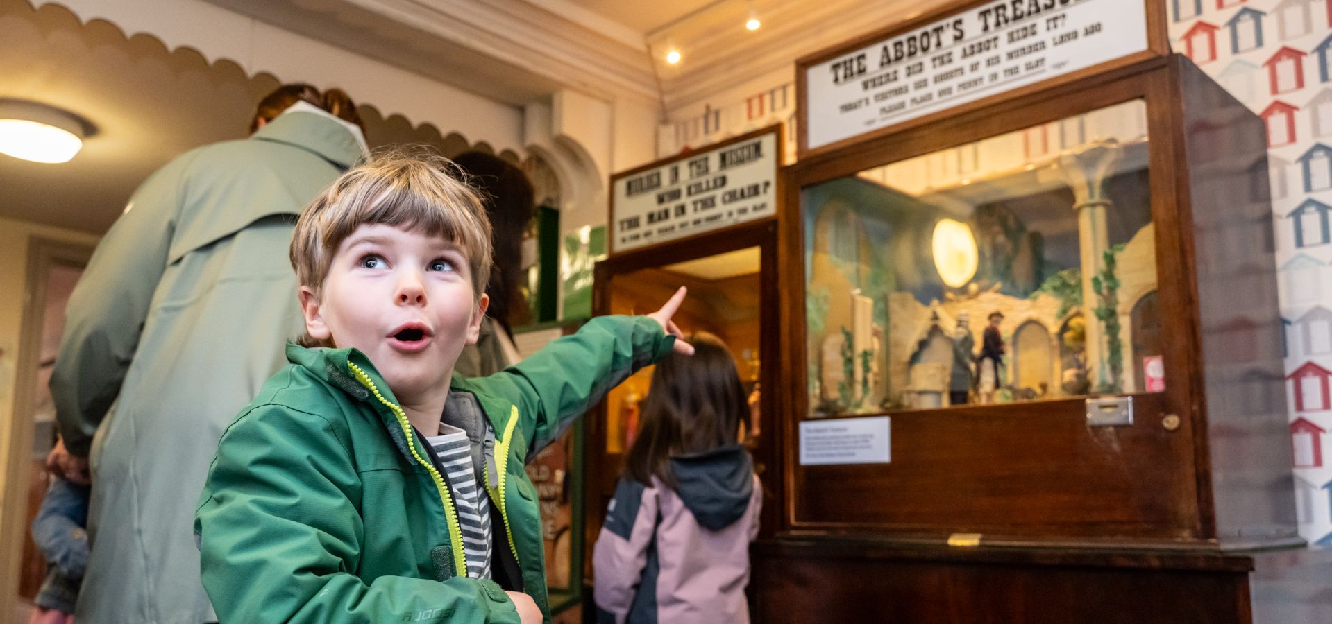 Young child pointing at a penny slot machine at Abbey House Museum