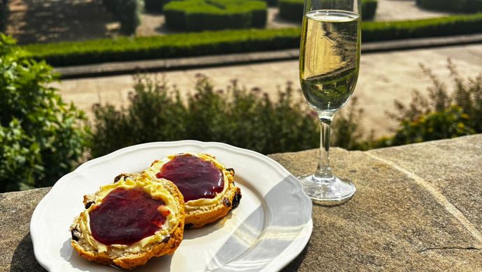 Scone with jam on a plate with a glass of prosecco on the terrace